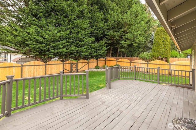 wooden terrace with a lawn and a fenced backyard