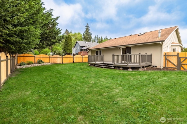 rear view of property featuring a fenced backyard, roof with shingles, a wooden deck, and a yard
