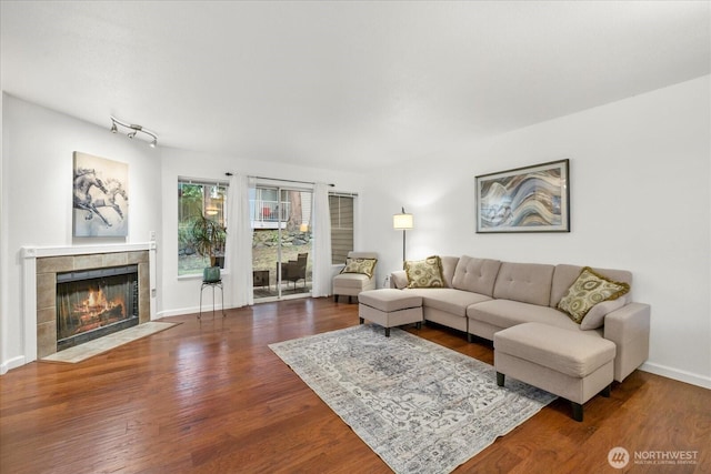 living area featuring baseboards, dark wood finished floors, and a tile fireplace
