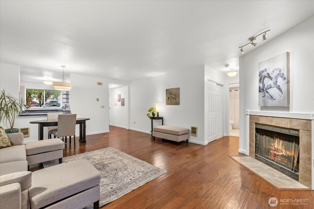 living room featuring baseboards, a tile fireplace, and wood finished floors