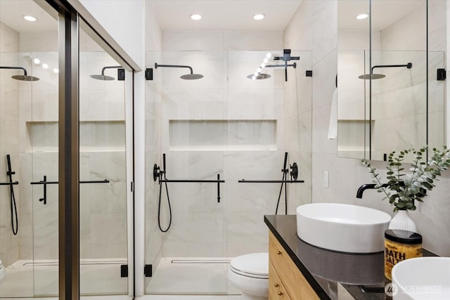 bathroom featuring vanity, tile walls, toilet, and a shower stall
