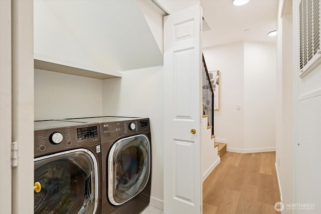 washroom with separate washer and dryer, laundry area, baseboards, and light wood-type flooring