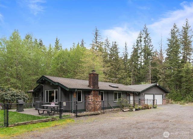 ranch-style house featuring a chimney, dirt driveway, fence private yard, a gate, and an attached garage