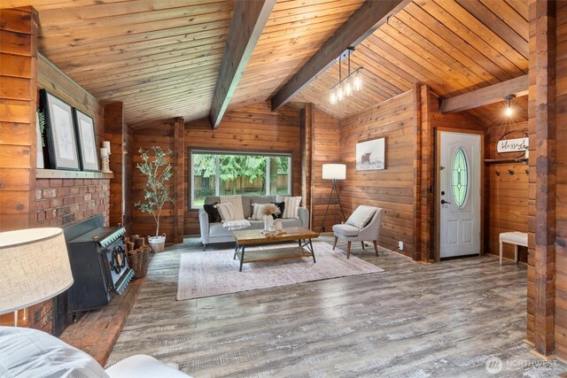 living area featuring vaulted ceiling with beams, wood walls, wood finished floors, and a wood stove