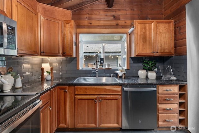 kitchen featuring decorative backsplash, appliances with stainless steel finishes, vaulted ceiling, brown cabinets, and a sink