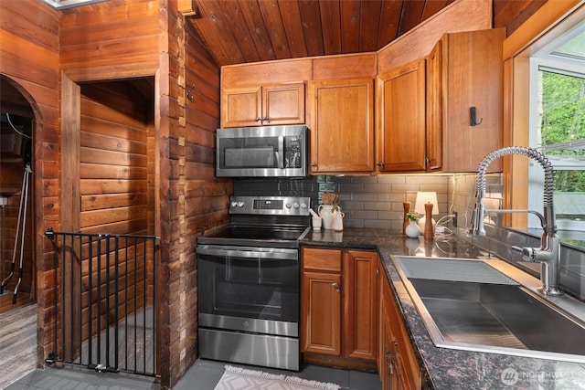 kitchen featuring brown cabinetry, a sink, appliances with stainless steel finishes, and wooden ceiling