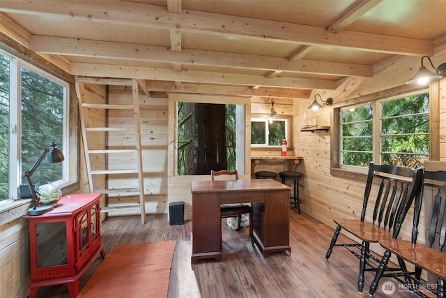 office area with wooden walls, beamed ceiling, a wood stove, and dark wood-style flooring