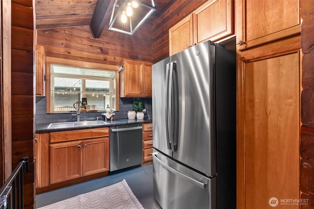 kitchen with decorative backsplash, dark countertops, a sink, vaulted ceiling with beams, and stainless steel appliances