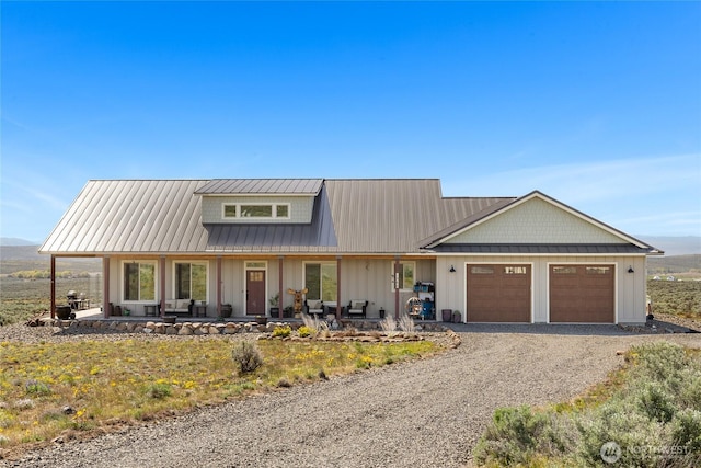 view of front of house with an attached garage, gravel driveway, board and batten siding, metal roof, and a porch
