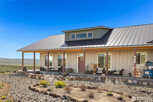 back of house featuring outdoor lounge area, a patio, a standing seam roof, board and batten siding, and metal roof