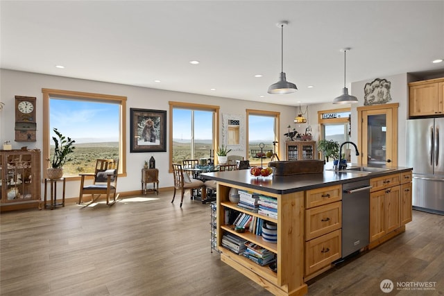 kitchen featuring open shelves, dark countertops, an island with sink, a sink, and appliances with stainless steel finishes