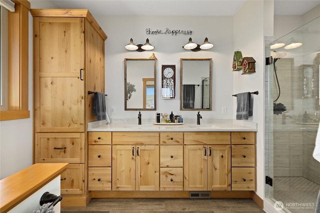 bathroom with double vanity, visible vents, a sink, and a stall shower