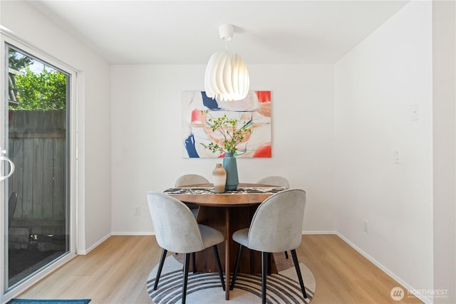 dining space featuring baseboards and light wood-type flooring