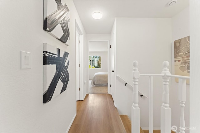 hall featuring baseboards, an upstairs landing, and light wood finished floors