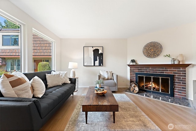 living area with baseboards, a fireplace, and wood finished floors