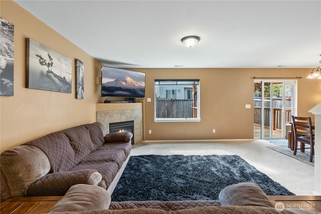 living area featuring carpet floors, baseboards, and a tiled fireplace