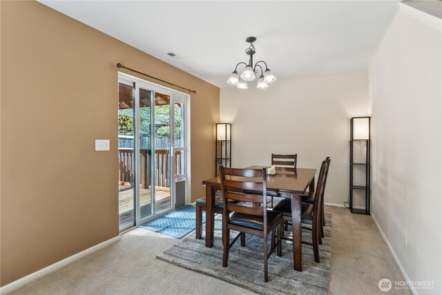 dining space with baseboards, a chandelier, and carpet