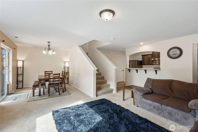 living room with light colored carpet, stairs, baseboards, and a chandelier