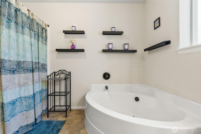 bathroom featuring tile patterned floors, baseboards, and a garden tub