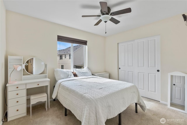 bedroom featuring baseboards, ceiling fan, a closet, and light colored carpet