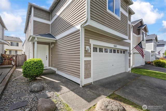 exterior space with an attached garage, fence, a residential view, and aphalt driveway