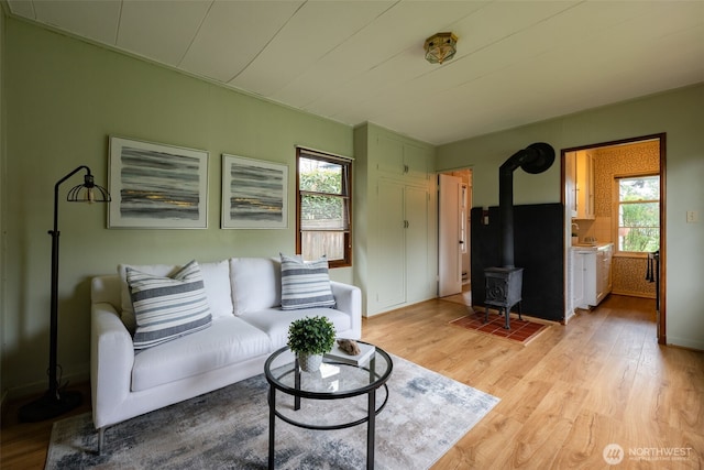 living area with a wood stove, light wood finished floors, and a healthy amount of sunlight