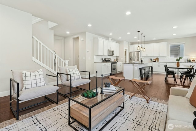 living room featuring recessed lighting, baseboards, stairway, and light wood-type flooring