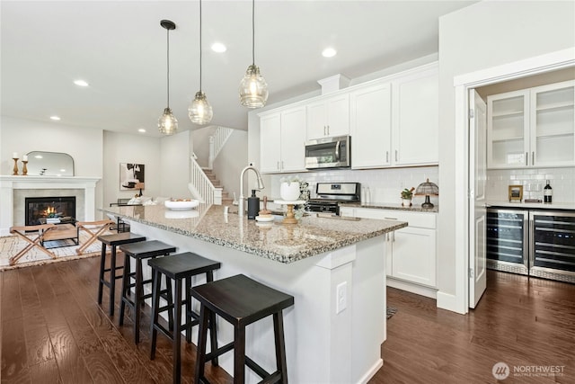 kitchen featuring a sink, appliances with stainless steel finishes, dark wood finished floors, and beverage cooler