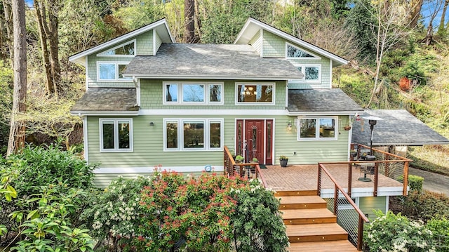 view of front of property featuring roof with shingles, a wooden deck, and stairway