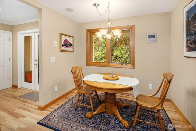 dining room with an inviting chandelier, baseboards, and light wood-style flooring