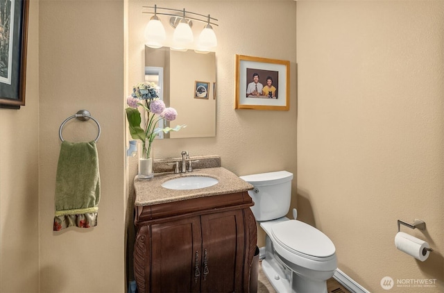 half bathroom with vanity, baseboards, and toilet