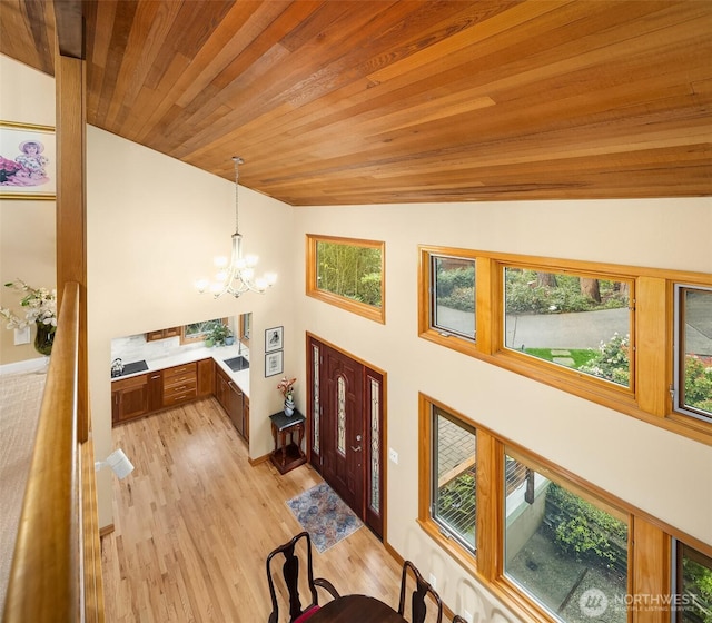 foyer entrance with light wood-style floors, wood ceiling, lofted ceiling, and a chandelier