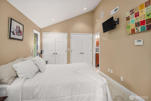 bedroom featuring light colored carpet, multiple closets, lofted ceiling, and visible vents