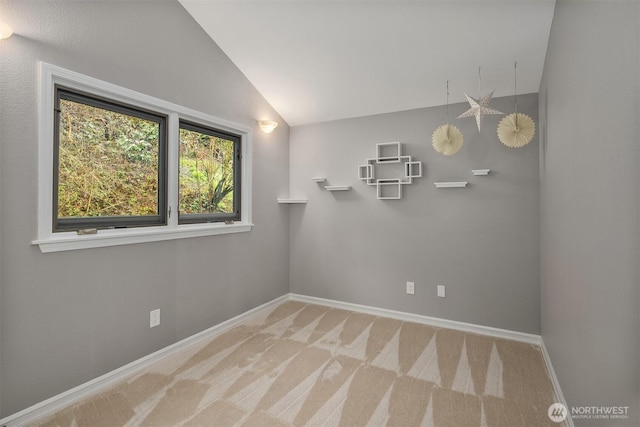 empty room with carpet floors, baseboards, and lofted ceiling