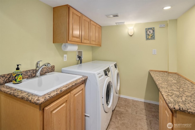 clothes washing area with cabinet space, a sink, baseboards, visible vents, and washing machine and dryer