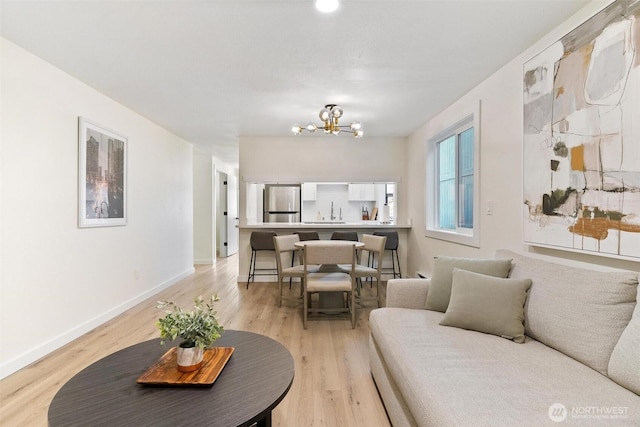 living area featuring light wood-type flooring, baseboards, and a chandelier