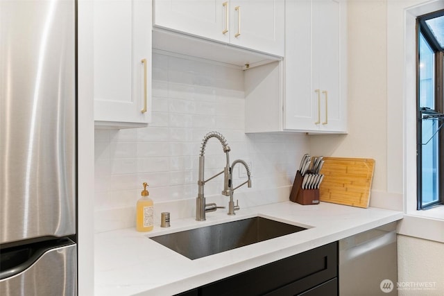 kitchen featuring a sink, appliances with stainless steel finishes, tasteful backsplash, and white cabinets