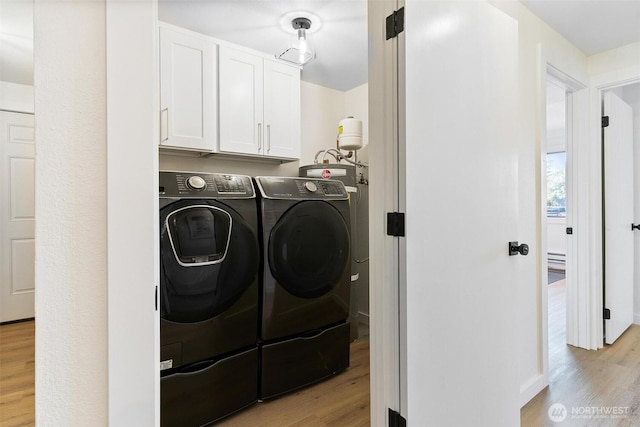 laundry area with light wood-style floors, cabinet space, and washing machine and clothes dryer