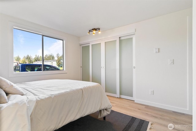 bedroom featuring baseboards, a closet, and light wood-style flooring