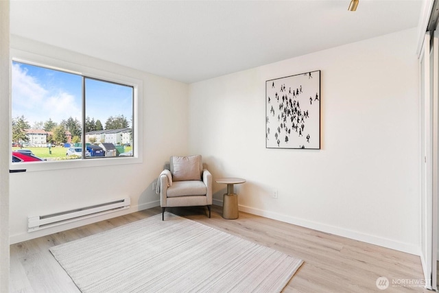 sitting room with baseboards, a baseboard radiator, and light wood-style flooring