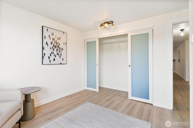 unfurnished bedroom featuring baseboards, wood finished floors, and a closet