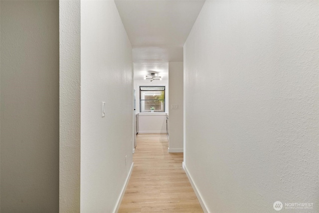 corridor with light wood-style floors and baseboards