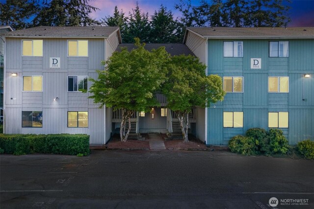 view of front of house featuring stairs, a shingled roof, and uncovered parking