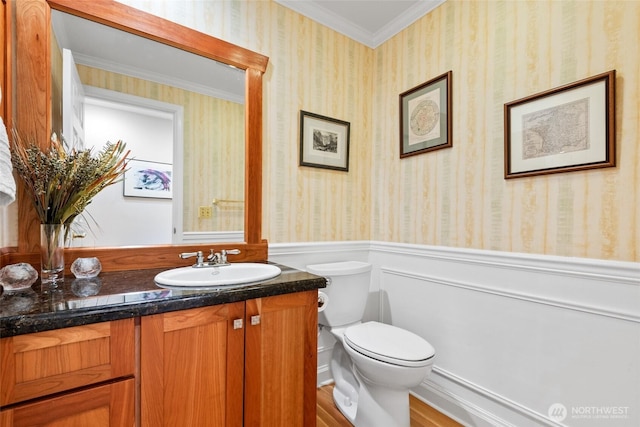 bathroom featuring a wainscoted wall, ornamental molding, wallpapered walls, toilet, and vanity
