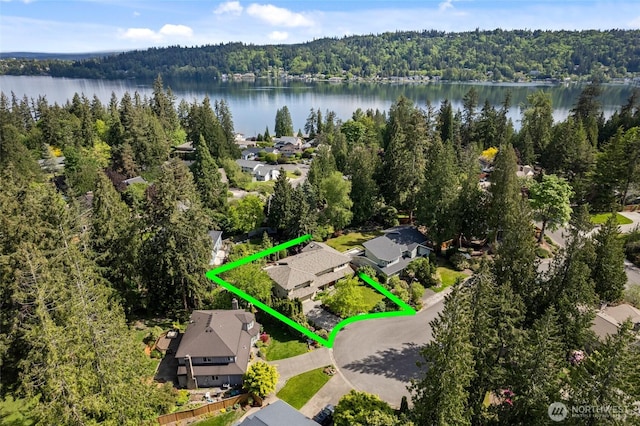 aerial view of residential area with a forest, property parcel outlined, and a nearby body of water