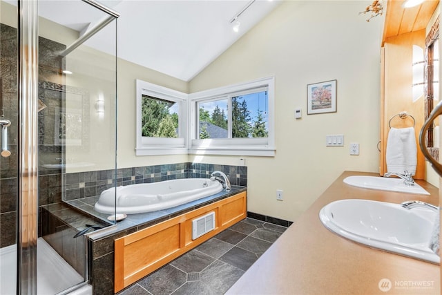 full bathroom with vaulted ceiling, a shower stall, a garden tub, baseboards, and double vanity