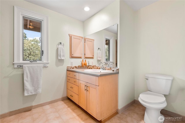 bathroom with toilet, vanity, and baseboards