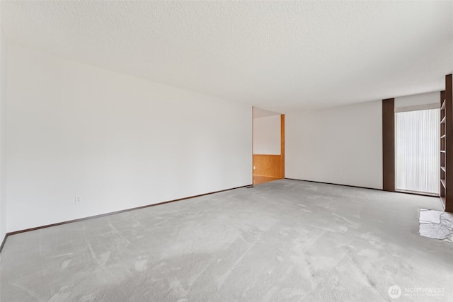 carpeted empty room featuring a textured ceiling and baseboards