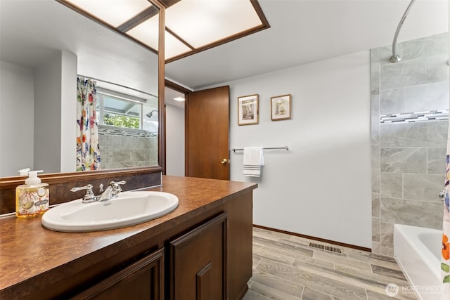 bathroom with visible vents, vanity, wood finished floors, shower / bath combination with curtain, and baseboards