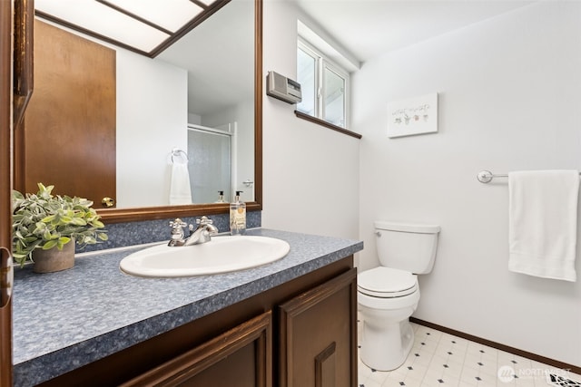 bathroom with vanity, toilet, baseboards, and a stall shower
